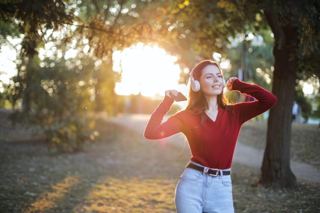 Young woman wearing the best Skullcandy headphone, listening to music in the park.