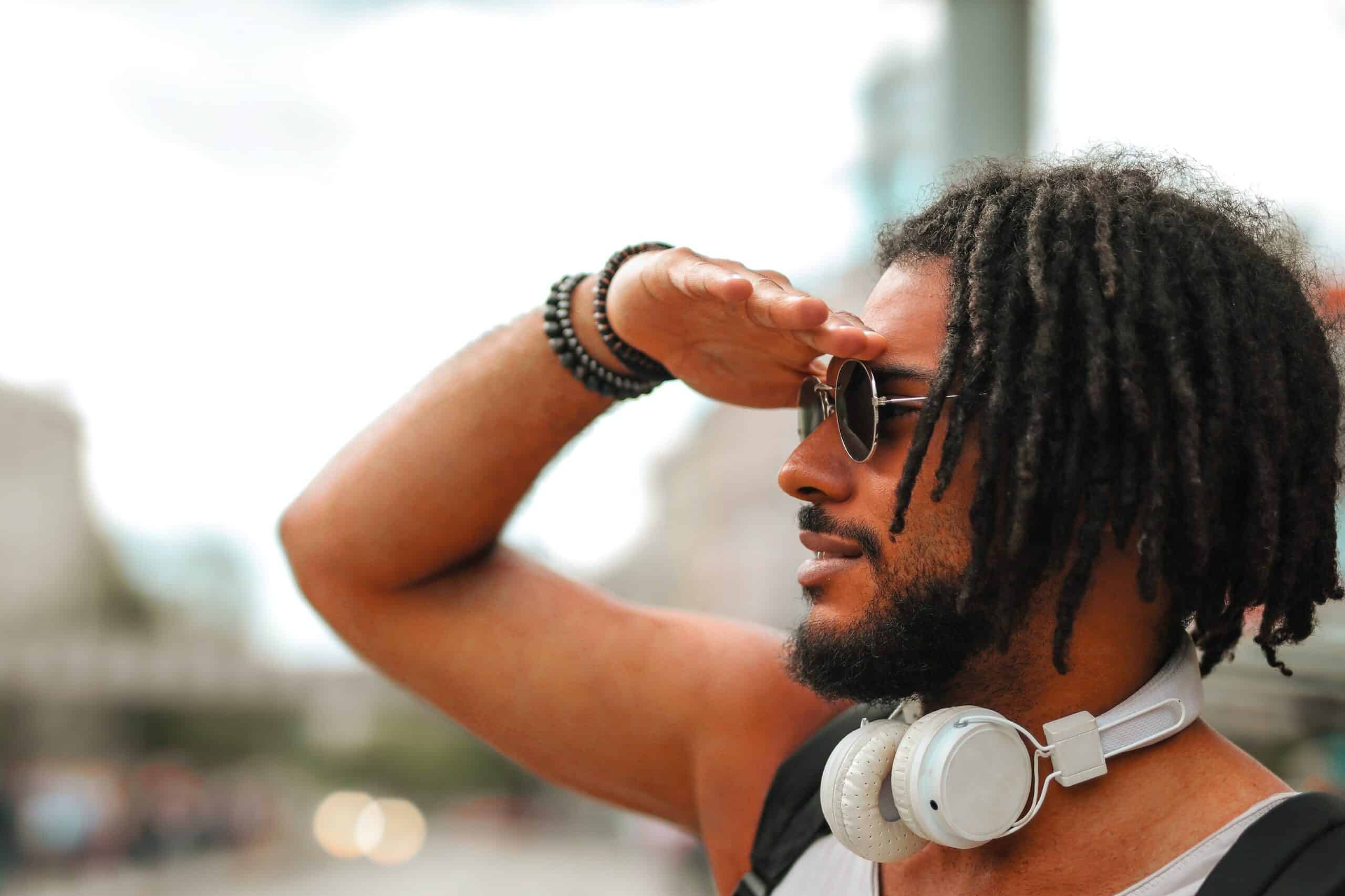 a man wearing the best skullcandy headphone with dreadlocks on a city street.