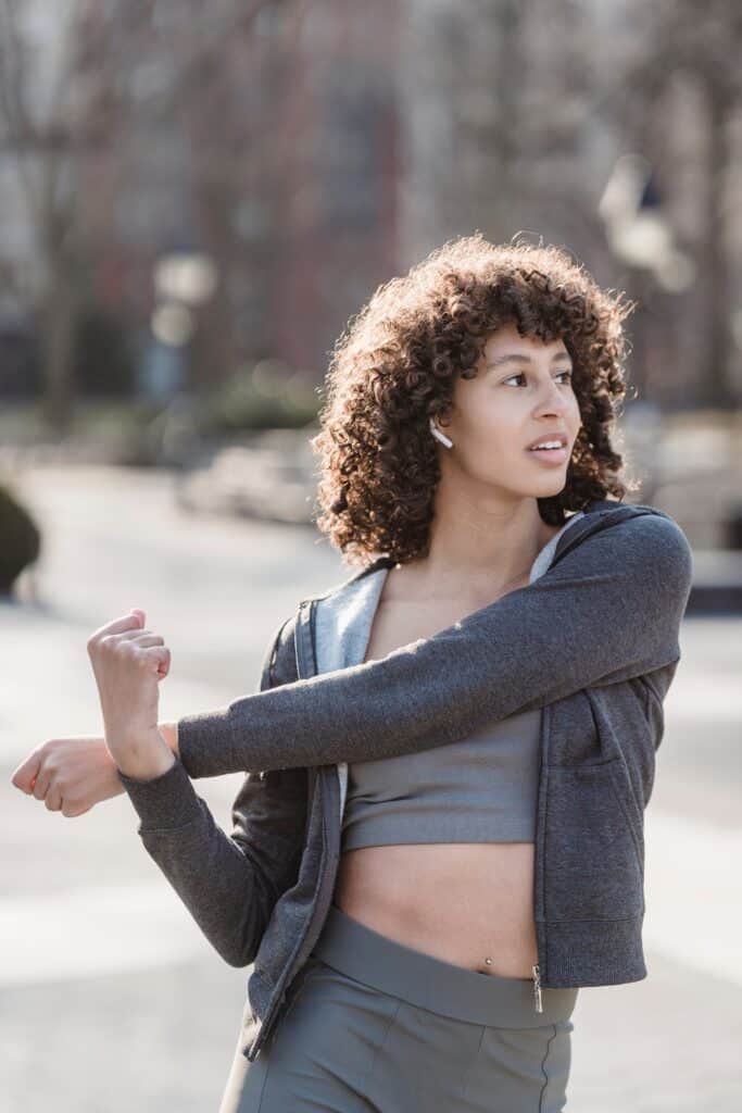 a women doing exercise in park with white skullcandy earbuds